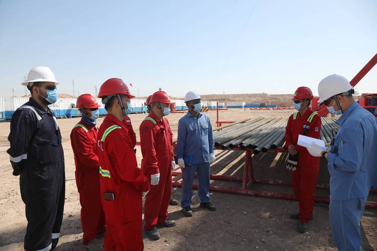 在伊拉克米桑油田,工程师王寿鑫(右一)与中伊双方井队人员进行技术